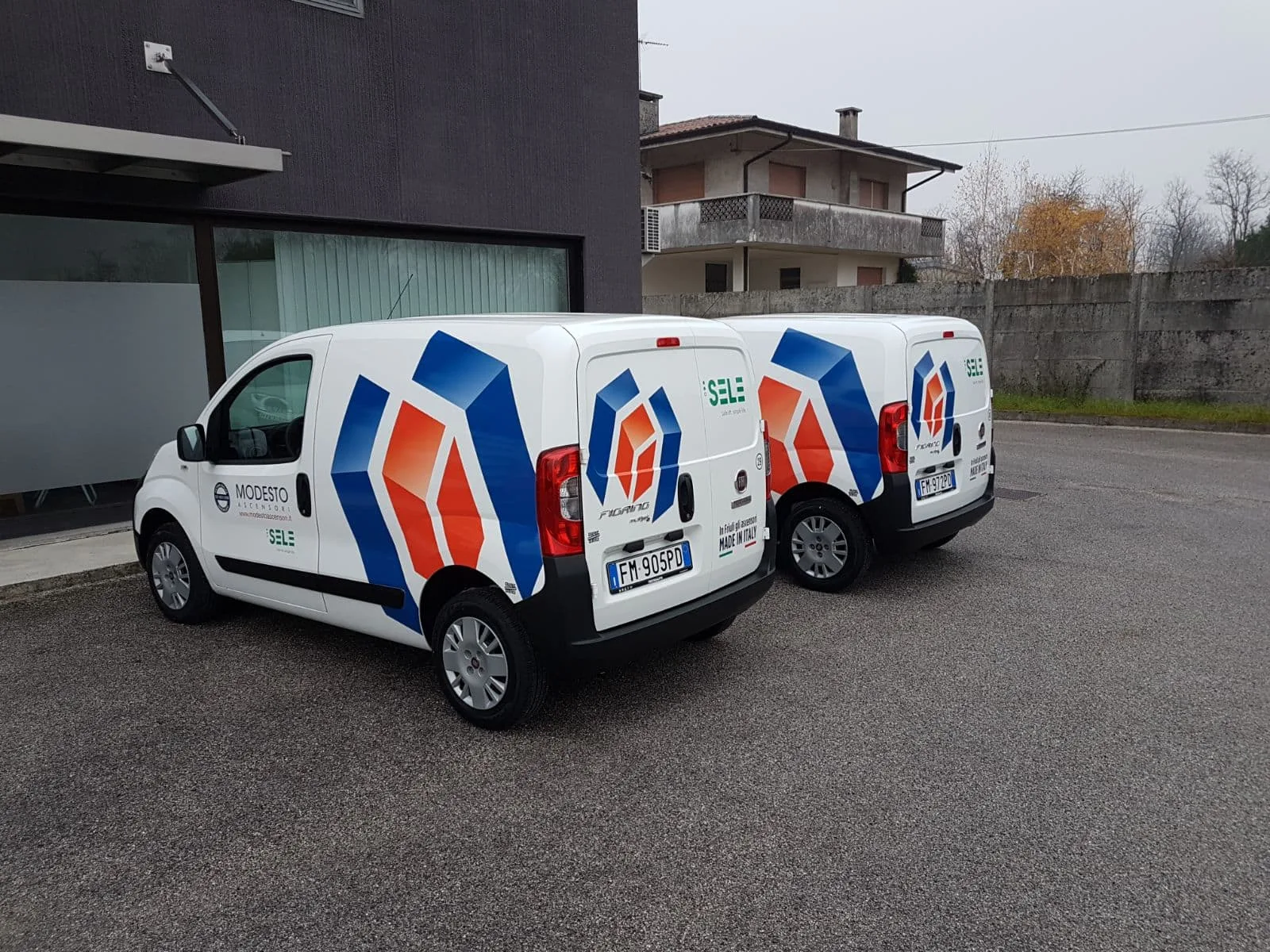 Furgone bianco di Solar Service con logo e numero verde in adesivo, visto da dietro con le montagne sullo sfondo