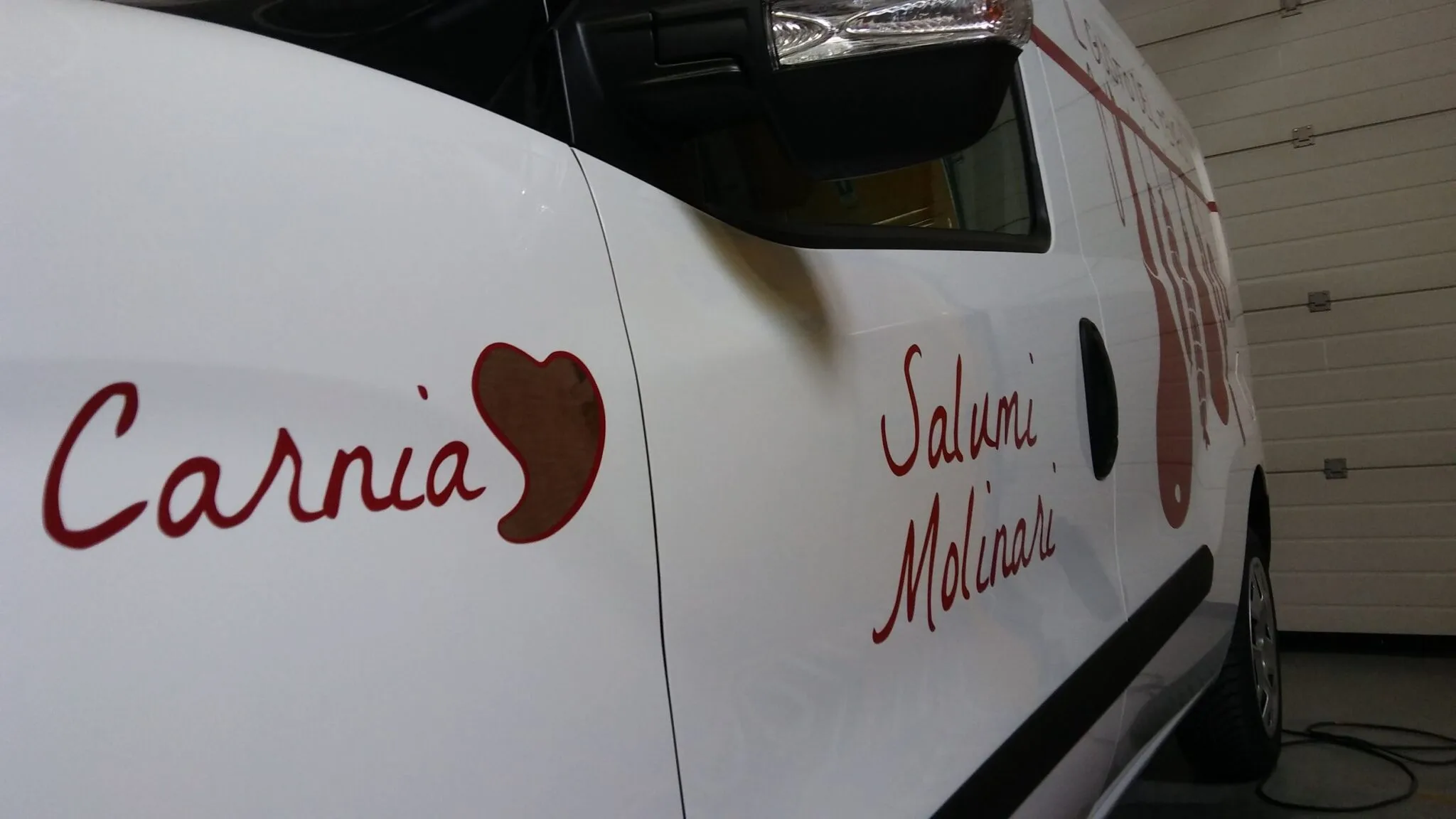 Dettaglio della portiera del furgone Molinari con cuore Carnia e scritta Salumi Molinari in adesivo