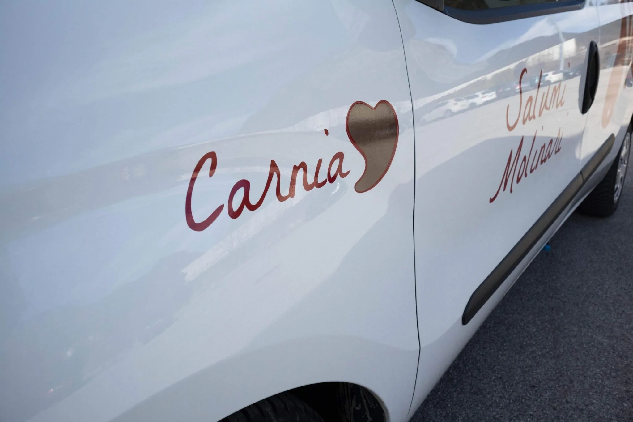 Scritta Carnia con cuore e Salumi Molinari in pellicola rossa sulla portiera del furgone