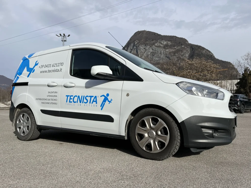 Ford Transit Courier di Tecnista decorato con l'omino azzurro e il marchio, fotografato in Carnia