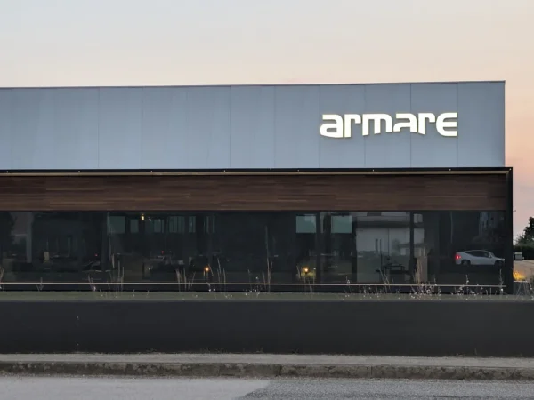 Il capannone di Armare a San Giorgio di Nogaro al tramonto, con il logo a lettere singole luminose
