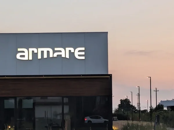 Il logo armare a lettere singole scatolate a luce diretta sul capannone, contro il cielo del tramonto