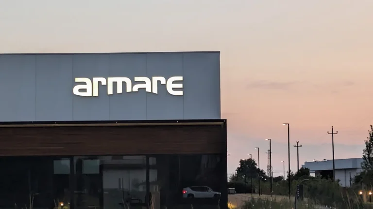 Il logo armare a lettere singole scatolate a luce diretta sul capannone, contro il cielo del tramonto