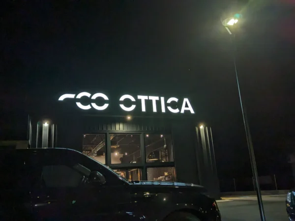 Insegna luminosa Comelstile a Buja di notte, lettere bianche a luce diretta