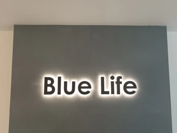 Insegna a lettere singole "Blue Life" a luce riflessa su parete chiara