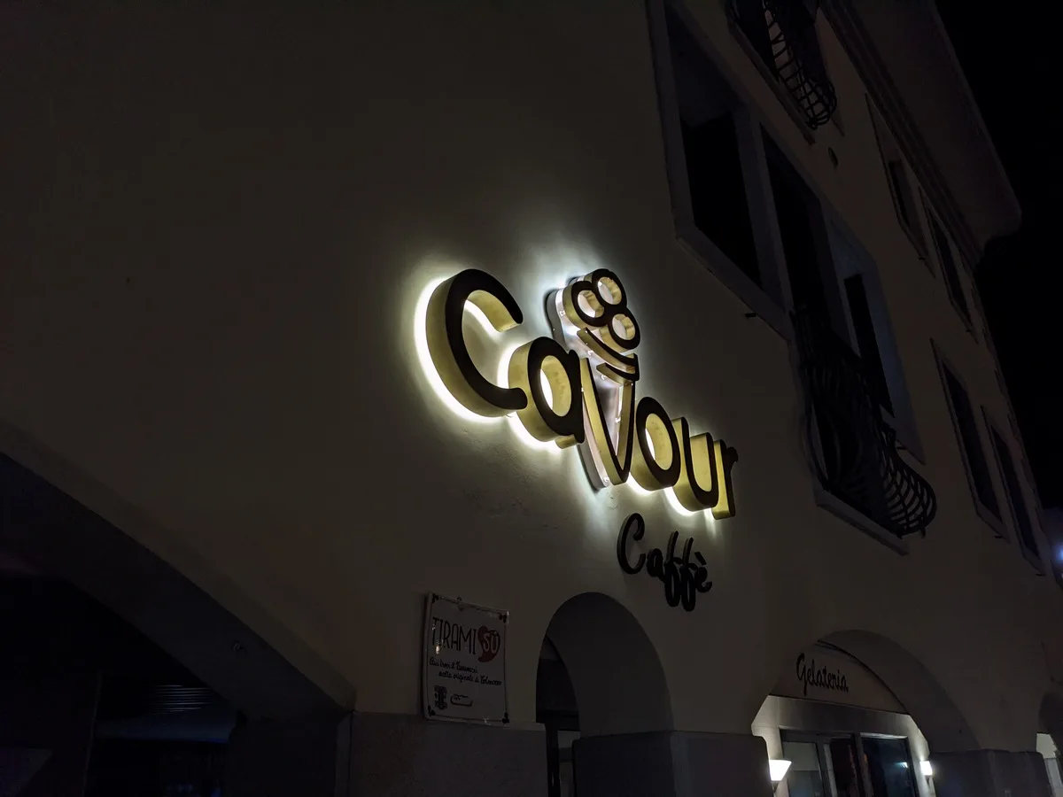 Cono gelato in ottone dell'insegna Cavour, appoggiato sul banco in officina con il led acceso