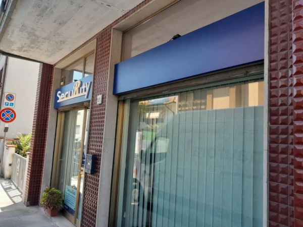 La facciata di Security a Monfalcone con le insegne blu sopra le vetrine e la porta