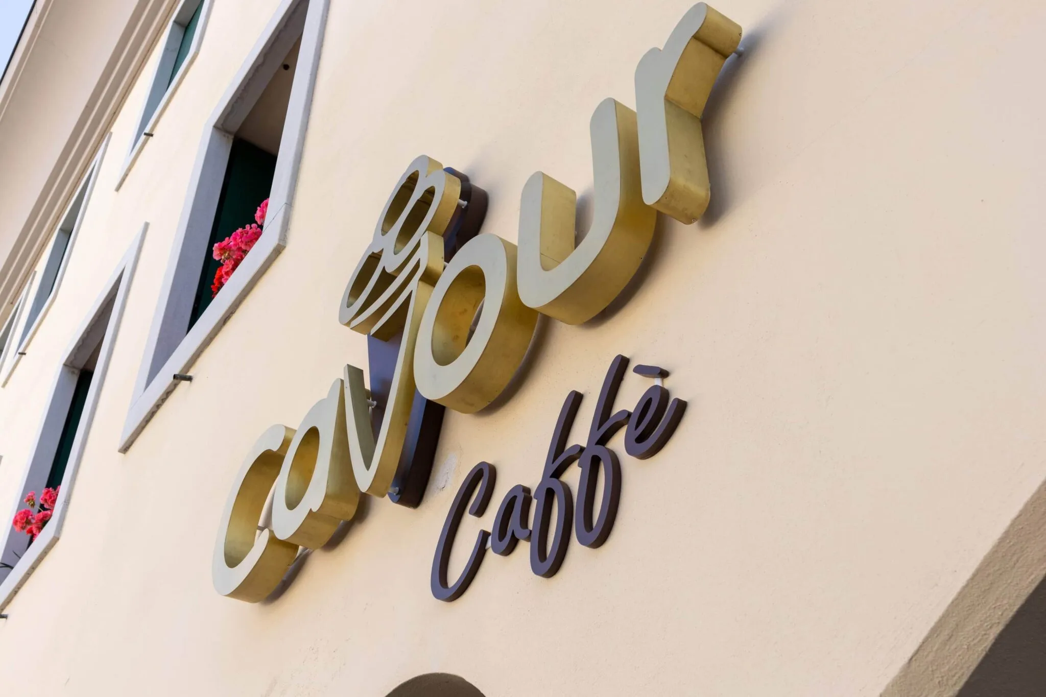 Lettere in ottone dell'insegna Cavour Caffè viste di scorcio, con il cono gelato in rilievo