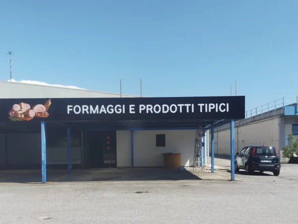 La fascia &laquo;Formaggi e prodotti tipici&raquo; sulla tettoia dello spaccio Zecchini