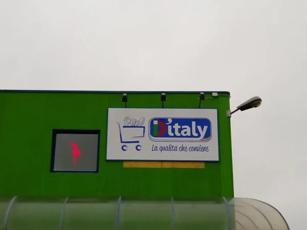 Il pannello sagomato D'Italy «la qualità che conviene» sulla facciata verde, da vicino