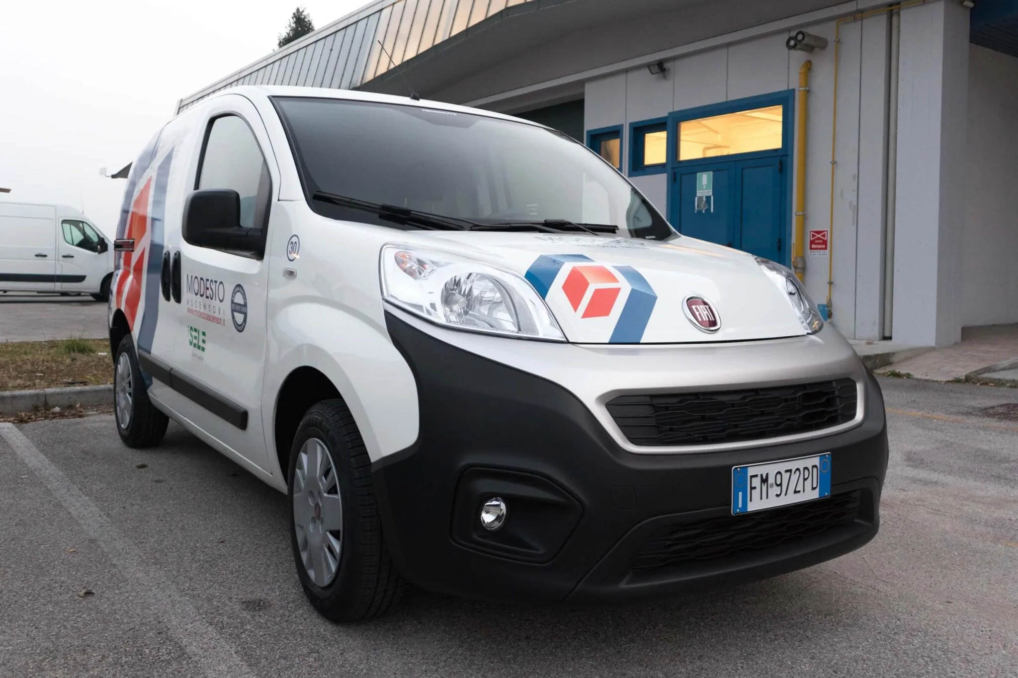 Fiat Fiorino bianco di Modesto Ascensori visto davanti con il logo adesivo sul cofano e le scritte sulla porta
