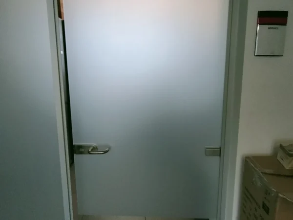 Porta in vetro di un ufficio GasGas con il sabbiato pieno, vista dal corridoio