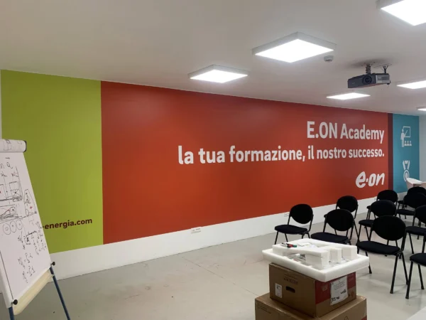 Sala corsi E.ON Academy con il murale rosso, verde e azzurro lungo tutta la parete e le sedie per la formazione