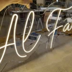 Scritta Al Faro in neon LED bianco accesa sul banco dell'officina, prima della consegna al Camping Lago dei Tre Comuni