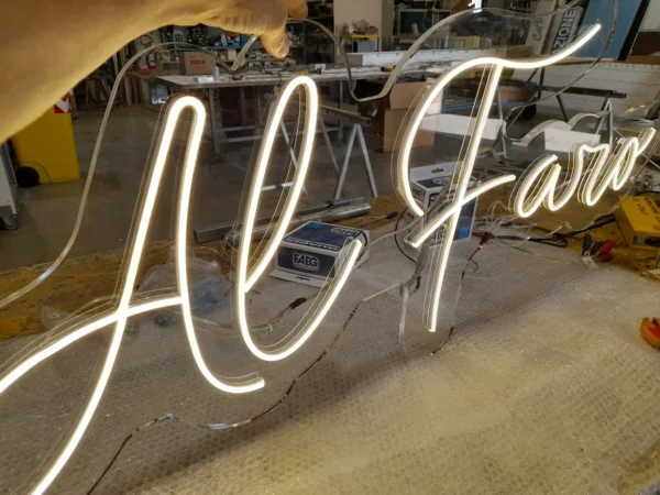 Scritta Al Faro in neon LED bianco accesa sul banco dell'officina, prima della consegna al Camping Lago dei Tre Comuni
