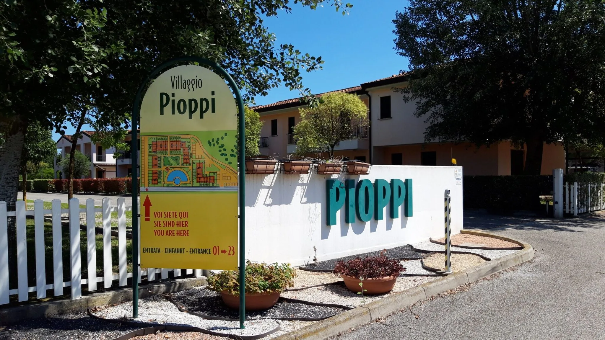 Cartello a mappa Voi siete qui del Villaggio Pioppi, accanto alla scritta Pioppi sul muro d'ingresso