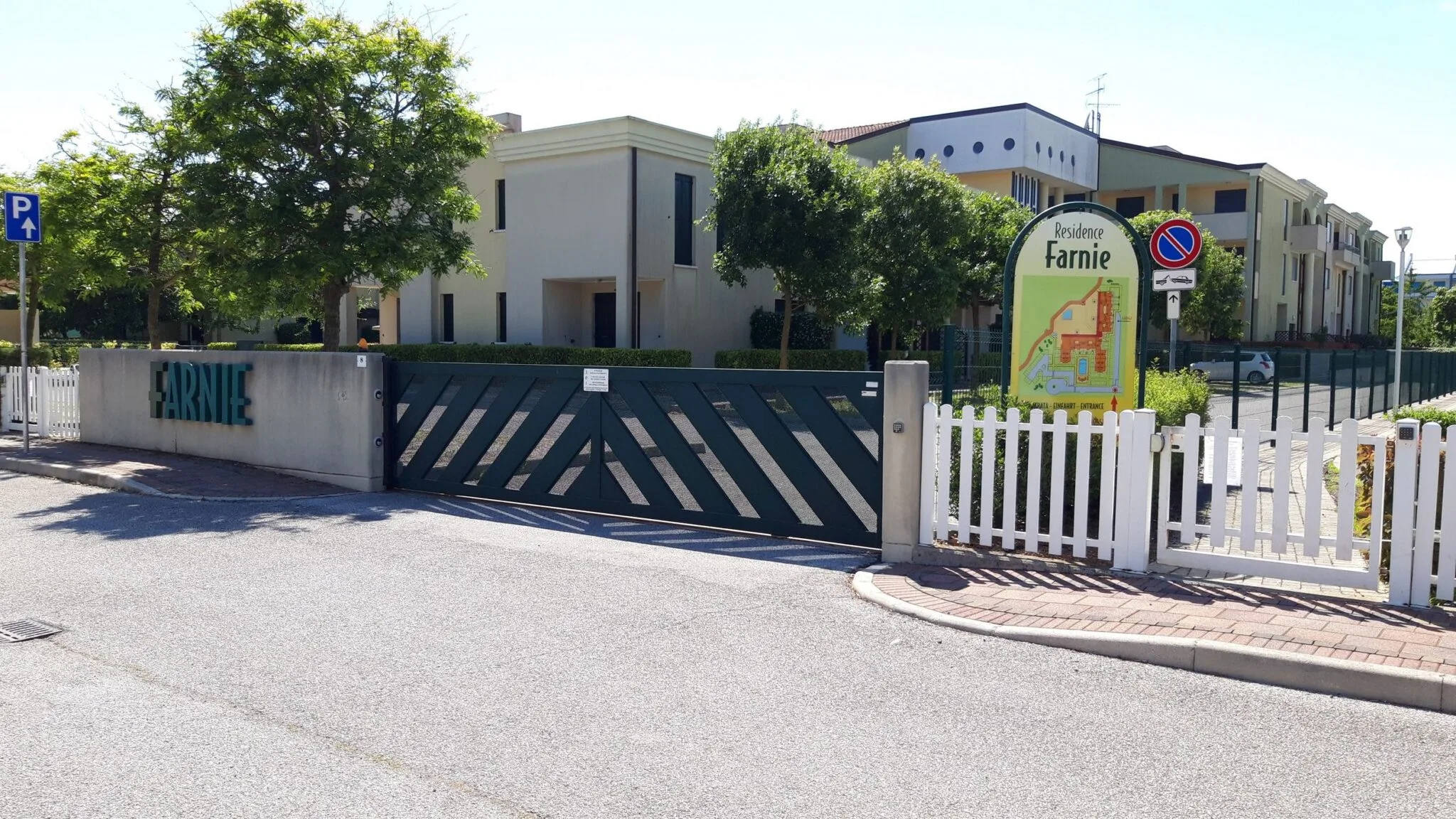 Cartello della Residence Farnie con mappa del complesso, accanto al cancello verde e alla scritta Farnie