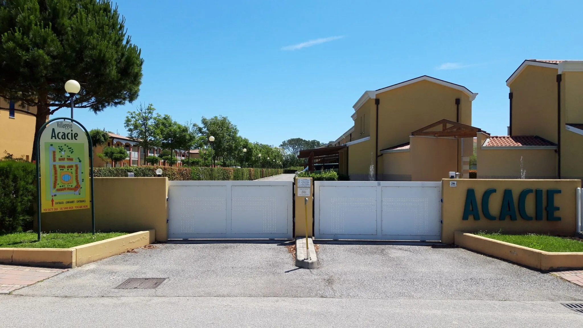 Cartello a mappa del Villaggio Acacie davanti all'ingresso con cancello bianco e scritta Acacie