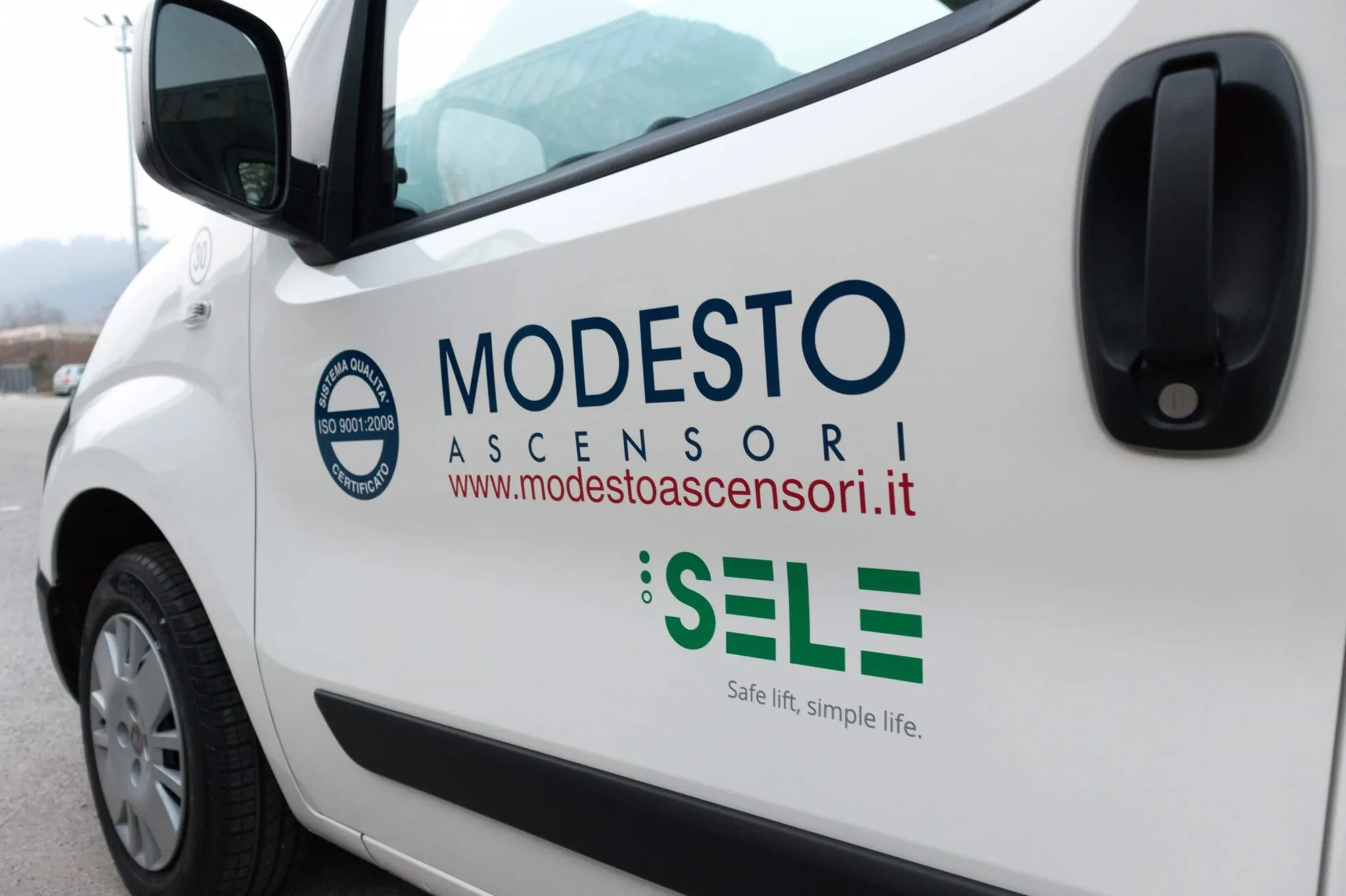 Portiera del furgone con logo Modesto Ascensori, marchio ISO 9001, sito web e logo Sele in adesivo