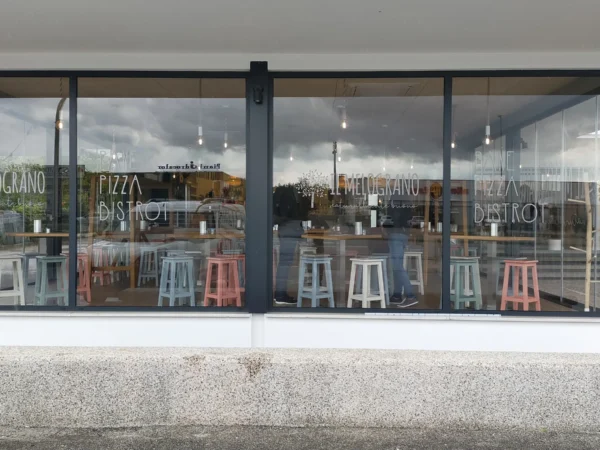 Vetrate del Melograno viste di fronte, con il logo e le scritte del locale in sabbiato