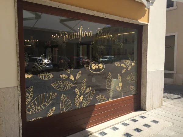 Vetrina d'angolo del Panificio Simeoni con le foglie e i chicchi di caffè in vinile oro lucido