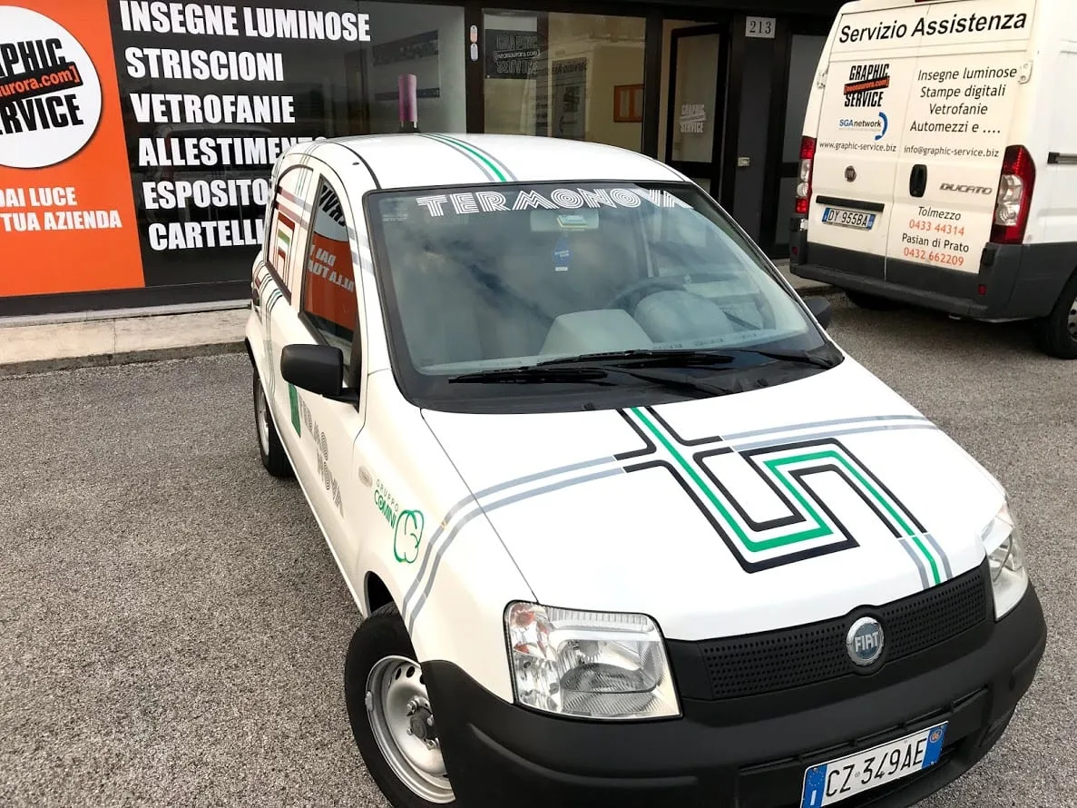 Frontale della Panda Termonova con la grafica adesiva sul cofano e sul tetto, davanti alla vetrina