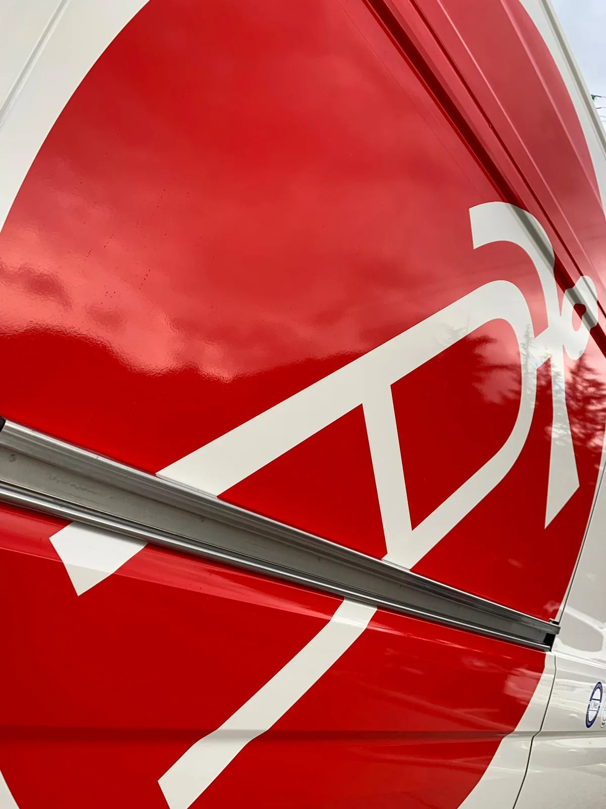 Primo piano del logo rosso e bianco di Antincendio Service in pellicola lucida sulla fiancata del furgone